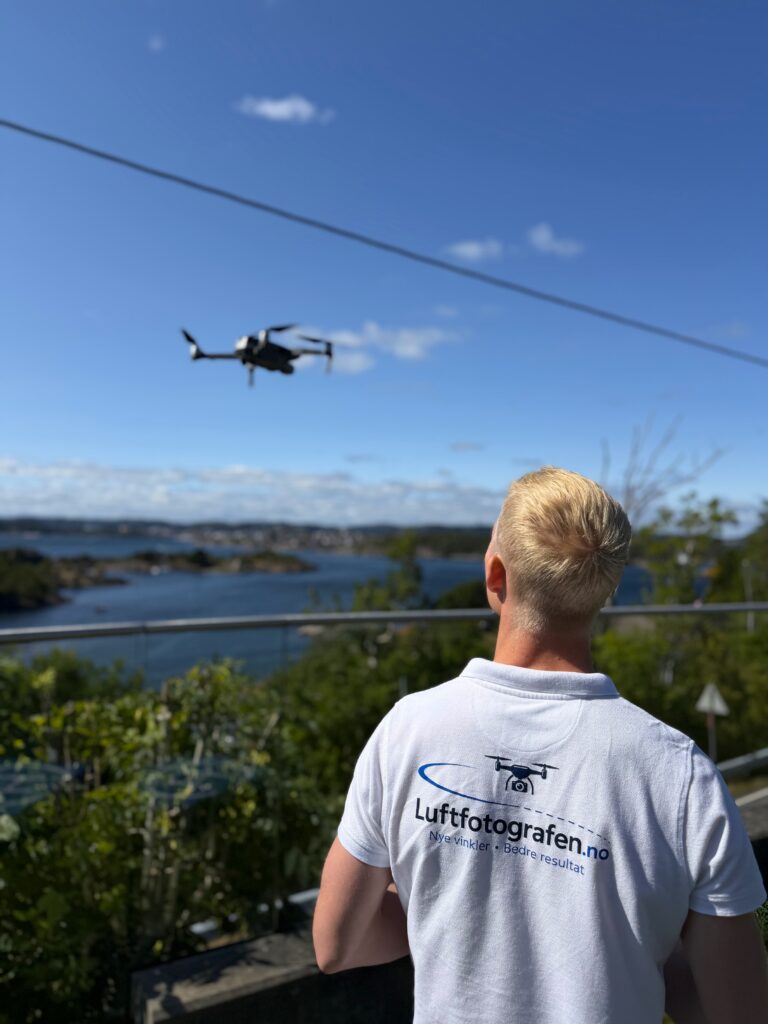 Dronepilot ser på drone Luftfotografen dronepilot Carl Martin Linnebo tar bilder av hus med drone